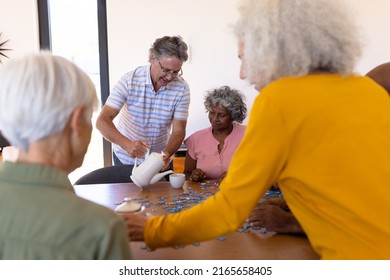 Caucasian senior man serving coffee to multiracial friends playing jigsaw puzzle in nursing home. Game, confusion, brainstorming, unaltered, togetherness, support, assisted living and retirement. - Powered by Shutterstock