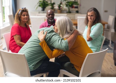 Caucasian senior man and woman embracing during group therapy session. unaltered, support, alternative therapy, community outreach, mental wellbeing and social gathering. - Powered by Shutterstock