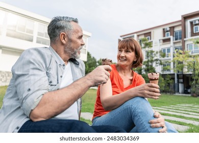 Caucasian senior man and woman having a picnic outdoors in the garden. Attractive elderly mature couple feeling happy and relax enjoy relationship after retired eating an ice cream together in park. - Powered by Shutterstock