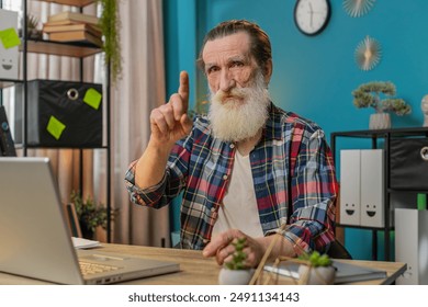 Caucasian senior man working on laptop shakes finger and saying No be careful scolding and giving advice to avoid danger mistake disapproval sign at home office. Freelancer grandfather sitting at desk - Powered by Shutterstock