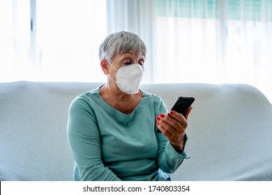 Caucasian Senior Woman Sitting With Face Mask Looking At Mobile Phone