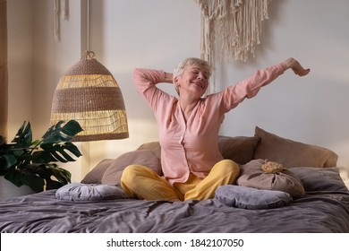 Caucasian senior woman wearing pyjama smiling in bright living room stretching waking up. - Powered by Shutterstock