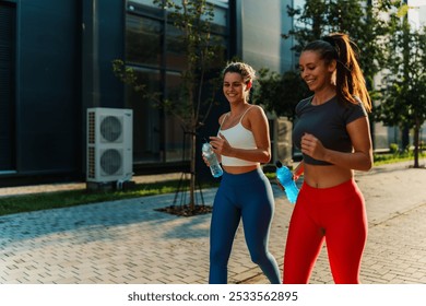 Caucasian sisters running outdoors, smiling and bonding through their fitness routine. - Powered by Shutterstock