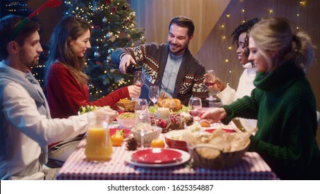 Caucasian Smiling Happy Man Host Pouring Wine Into Glasses Treating His Friends Guests Welcoming Celebrating Christmas Dinner And Holidays Together.