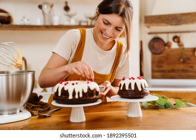 Caucasian smiling pastry chef woman making chocolate cake at cozy kitchen