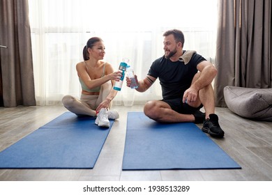 caucasian sportive couple after training workout at home, take a break sitting on fitness mat