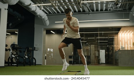 Caucasian sportsman man footballer soccer player training in sports gym exercise with ladder sport equipment workout cardio exercising jumping prepare for football match male athlete in fitness club