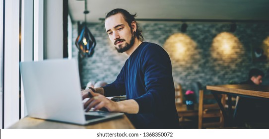 Caucasian Student Watching Webinar On Laptop Computer Improving Skills On Programming, Serious Professional Web Designer Working On Freelance Sitting In Cafeteria And Using Good Wifi Connection