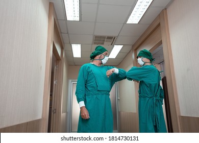 Caucasian Surgeon Doctor Elbow Bump Greeting For Social Distancing With Friend Co-worker In Hospital Hallway. New Normal Etiquette Concept During Coronavirus Or Covid-19. Healthcare And Medical