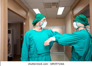 Caucasian Surgeon Doctor Elbow Bump Greeting For Social Distancing With Friend Co-worker In Hospital Hallway. New Normal Etiquette Concept During Coronavirus Or Covid-19. Healthcare And Medical