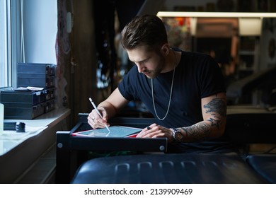 Caucasian tattoo artist  designing motifs on digital tablet  - Shutterstock ID 2139909469