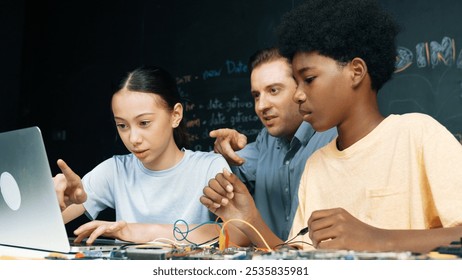 Caucasian teacher pointing at laptop while teaching about engineering code. Instructor working by using laptop while happy highschool student learning and studying programing system. Edification. - Powered by Shutterstock