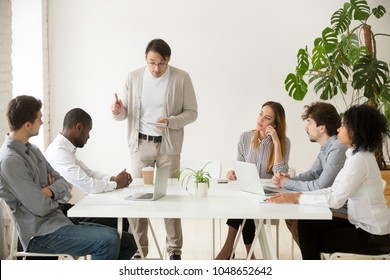 Caucasian team leader rebuking african employee for mistake at group meeting, black office worker getting last warning from boss dissatisfied with bad work results reprimanding scolding subordinate