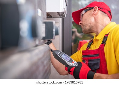 Caucasian Technician In His 40s With Gas Leak Detector Performing Scheduled Check And Heating Furnace Maintenance. HVAC Worker