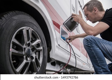 Caucasian Technician Trying To Fix RV Travel Trailer Electric Hookup Problem Looking Inside Outside Compartment. - Shutterstock ID 1493792786