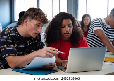 Caucasian teen boy and black teenage female high school students in class working together on school project using laptop. - Powered by Shutterstock