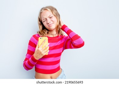 Caucasian Teen Girl Holding Mobile Phone Isolated On Blue Background Touching Back Of Head, Thinking And Making A Choice.