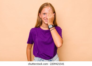 Caucasian Teen Girl Isolated On Beige Background Having Fun Covering Half Of Face With Palm.