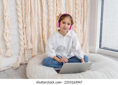 Caucasian teen girl school pupil in headphones studying online from home. Remote education concept. Teenager distance learning on laptop, doing homework, watching, listening video lesson. Copy space - Shutterstock ID 2253163947