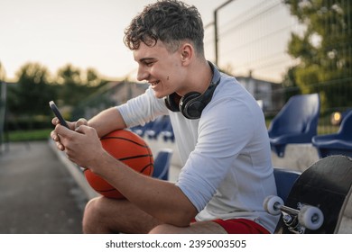 caucasian teen using mobile phone smartphone at a basketball court - Powered by Shutterstock