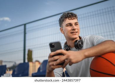 caucasian teen using mobile phone smartphone at a basketball court - Powered by Shutterstock