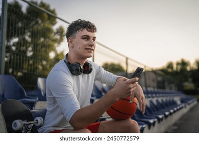 caucasian teen using mobile phone smartphone at a basketball court - Powered by Shutterstock