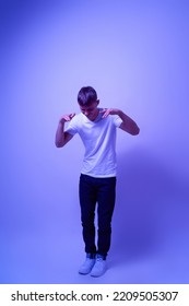 Caucasian Teenage Boy Listening Music In Wireless Earphoness And Dancing. Guy Of Zoomer Generation. Concept Of Modern Youngster Lifestyle. Isolated On Blue With White Light. Studio Shoot. Copy Space