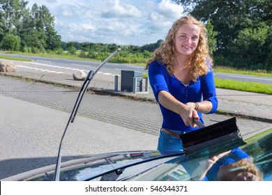 Caucasian teenage girl cleaning car windshield - Powered by Shutterstock