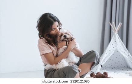 Caucasian teenage girl playing with shih tzu puppy dog at home. Young beautiful woman sitting on floor, having fun hugging little fluffy dog pet with love and care - Powered by Shutterstock