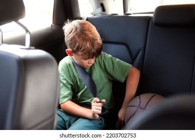 Caucasian  teenager boy in green T-shirt, sitting in the back seat of the car and fastens his seat belt - Powered by Shutterstock