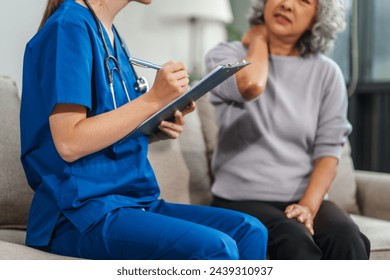 Caucasian teenager female doctor consults with and Asian elderly patient on medical history, discussing headaches, chest pain, coughing, sneezing, stomach pain, and neck pain while seated on a sofa. - Powered by Shutterstock
