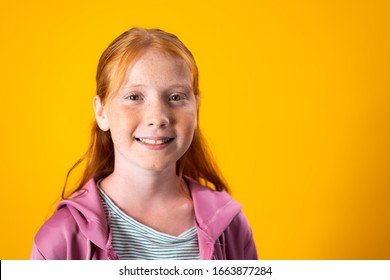 A Caucasian Teenager Girl With Red Hair And Freckles Posing For A Portrait Over Yellow Background With Copy Space. Concept Of Confident And Assertive Young Females. Gender Equality And Women's Rights.