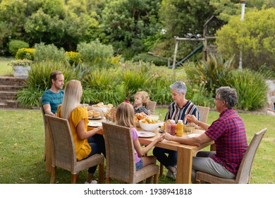 Une famille de trois générations du Caucase se tenant la main en disant grâce avant de manger ensemble dans le jardin. famille de trois générations célébrant la fête de l'indépendance mangeant ensemble à l'extérieur.