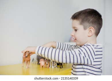 Caucasian toddler child playing with animal figurines toys in light room interior - Shutterstock ID 2135140339