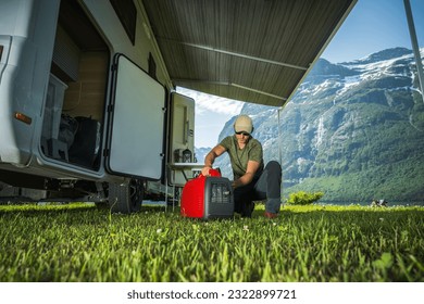 Caucasian Tourist and RV Owner Running Red Portable Inverter Generator To Hook Up the Camper Van. Vacation On the Road Theme. - Shutterstock ID 2322899721