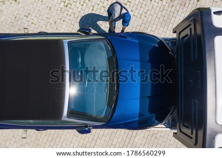 Caucasian Towing Truck Driver and Modern Repossessed Convertible Car Moving Back to Bank Owner. Repossession and Car Loans Theme. Aerial View.