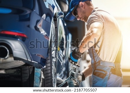 Caucasian Towing Worker Fastening Broken Vehicle with Tie Down Straps. Professional Roadside Assistance and Breakdown Coverage Services. Automotive and Transportation Industry.