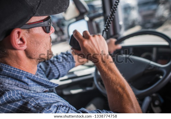 Caucasian Truck Driver in his 30s CB\
Talking with Other Drivers in the Convoy. Heavy Load Transportation\
Communication.