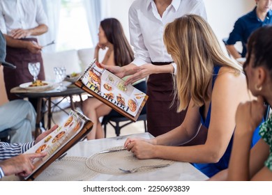 Caucasian waiter receiving order serving from customer in restaurant. Attractive server service man working, taking note, writing order from consumer with pen at table in dining room with happiness. - Powered by Shutterstock