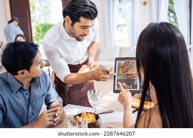 Caucasian waiter receiving order serving from customer in restaurant. Attractive server service man working, taking note, writing order from consumer with pen at table in dining room with happiness. - Powered by Shutterstock