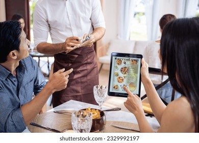 Caucasian waiter receiving order serving from customer in restaurant. Attractive server service man working, taking note, writing order from consumer with pen at table in dining room with happiness. - Powered by Shutterstock