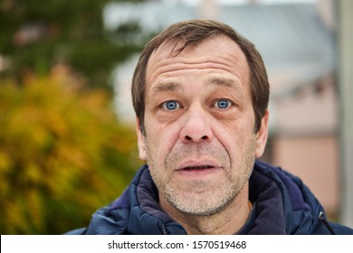 Caucasian White Surprised Man About 50 Years Old With Stubble On His Face Is Posing Outdoors In The Cold Fall. Portrait Of Stubbled Male Outside On The Street.