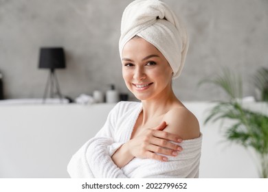 Caucasian White Woman With Clean Young Clear Skin In Spa Bath Towel Looking At The Camera. Beauty Treatment, Body And Hair Care. Girl After Taking Bath Shower At Home