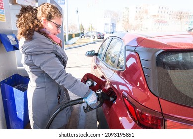 Caucasian White Woman Refueling Her Diesel Car At The Gas Station Wearing Plastic Gloves.