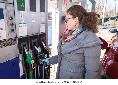 Caucasian White Woman Refueling Her Diesel Car At The Gas Station Wearing Plastic Gloves.