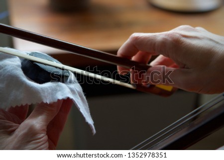 Caucasian woman applying cello rosin to the bow