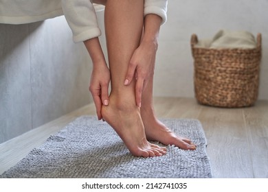 Caucasian woman in bathrobe applying moisturizing cream on heels - Shutterstock ID 2142741035