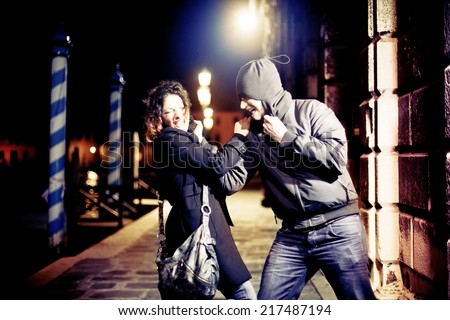 Caucasian woman being assaulted by a man in a dark alley.  Aggression concept.
