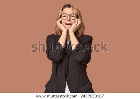 Caucasian woman in black business suit whining and crying disconsolately.