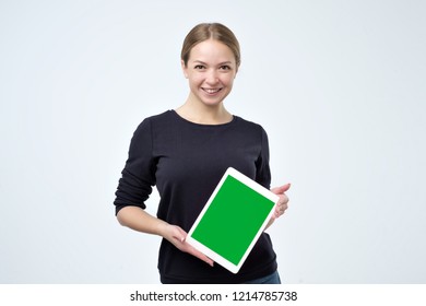 Caucasian woman in black clothes using digital tablet showing green screen isolated on white background. Put your advertisment here